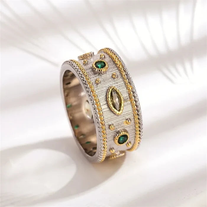Gold band ring with colorful inset stones shown on white background