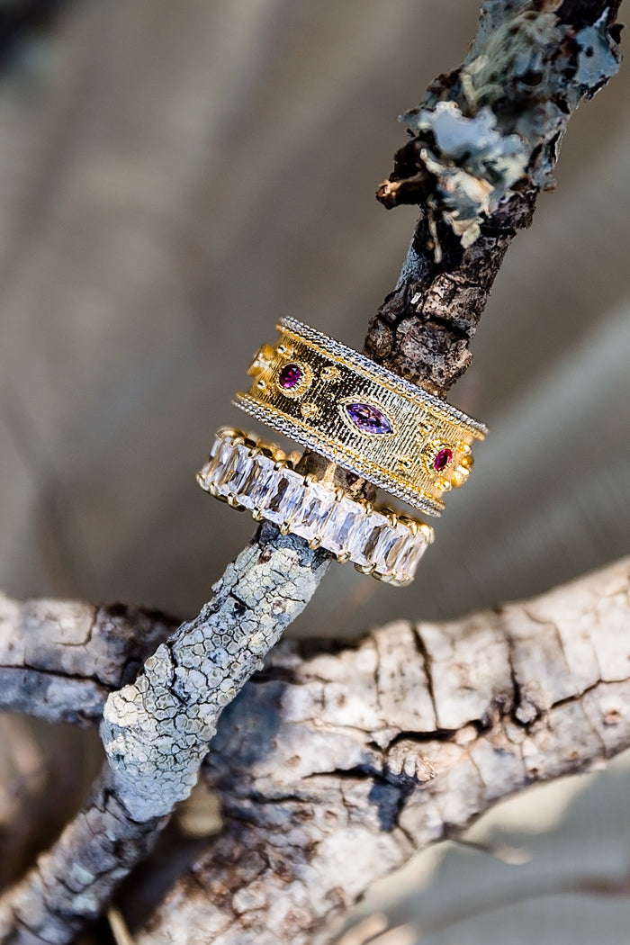 Close-up of gold statement ring with colorful stones styled on natural branch
