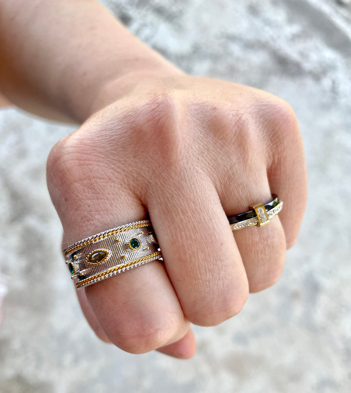 Gold statement ring with colorful stones worn on hand alongside other rings