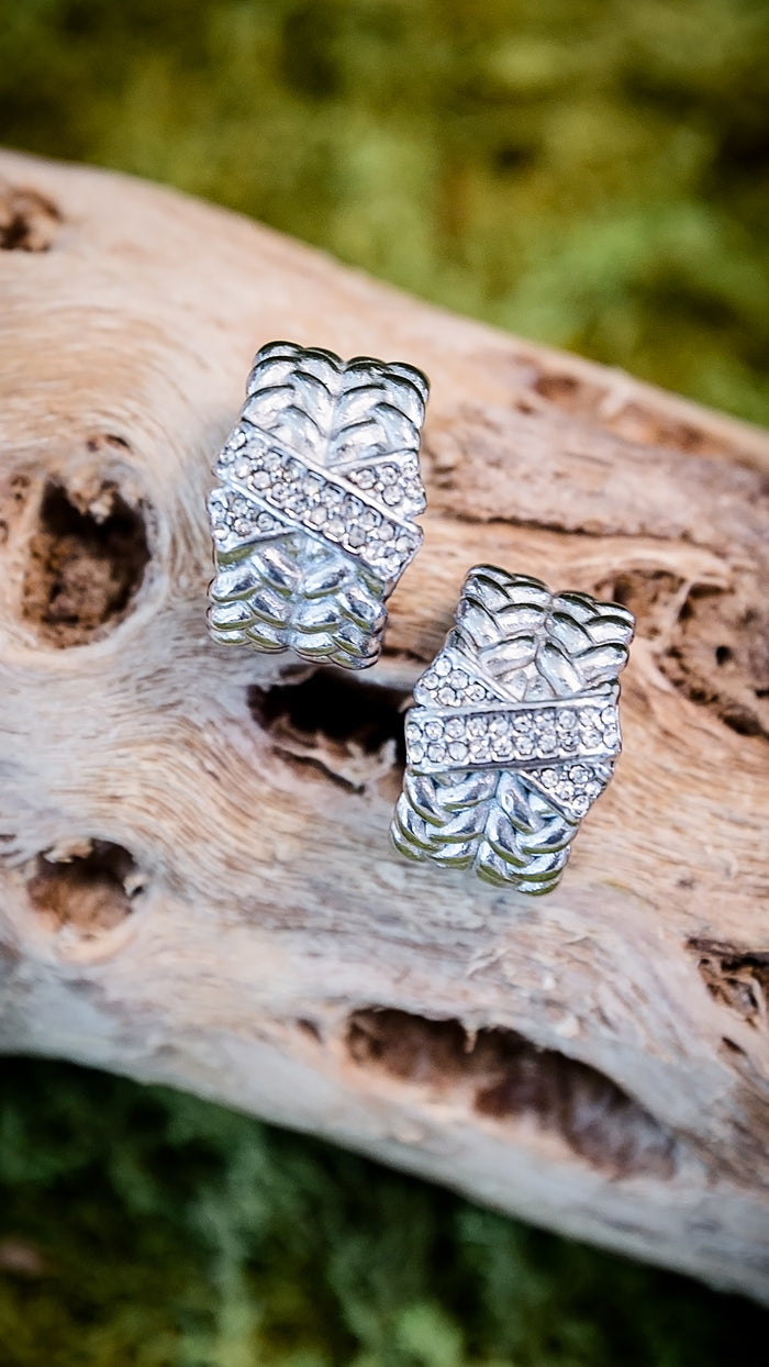 VEITA Jewelry silver chunky woven braided hoop earrings with pavé CZ stones displayed on driftwood with natural background