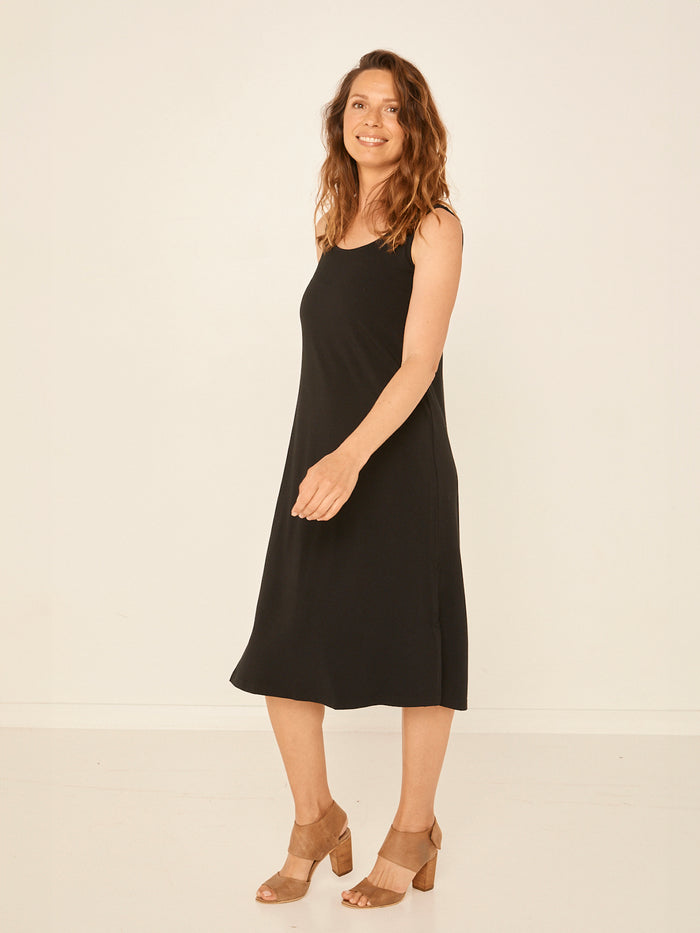 Model wearing a reversible black midi length a-line dress with scoop and boat necklines, women's bamboo clothing