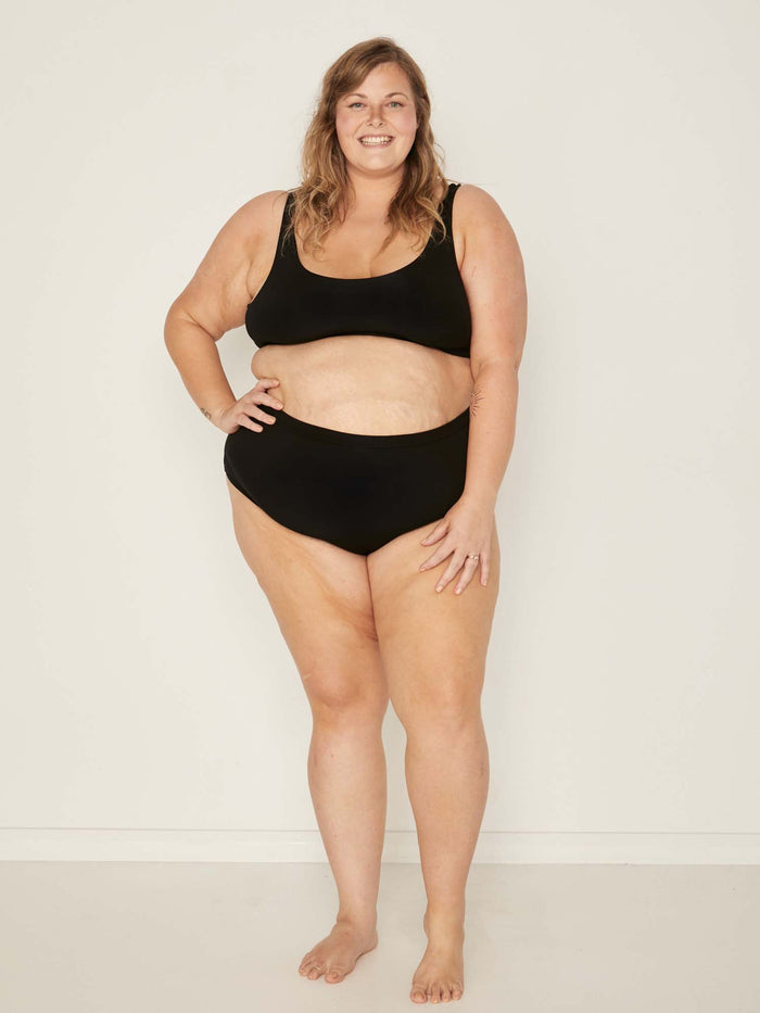 Model wearing black high waisted full brief with mid leg opening and double layered waistband, women's bamboo underwear