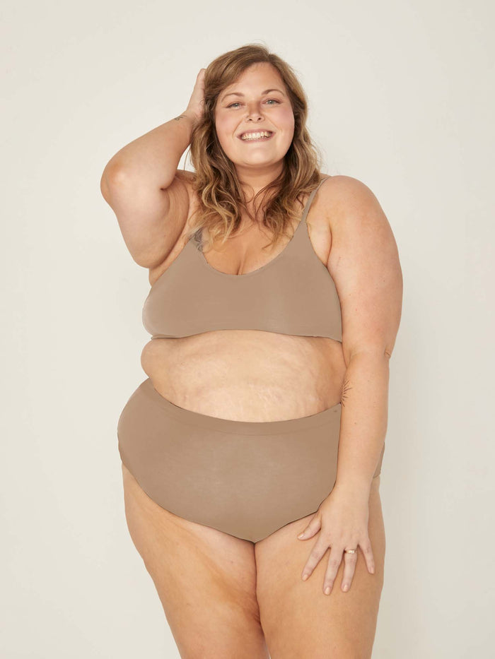 Model wearing caramel high waisted full brief with mid leg opening and double layered waistband, women's bamboo underwear