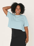 Woman wearing a light blue top and black skirt on a white background