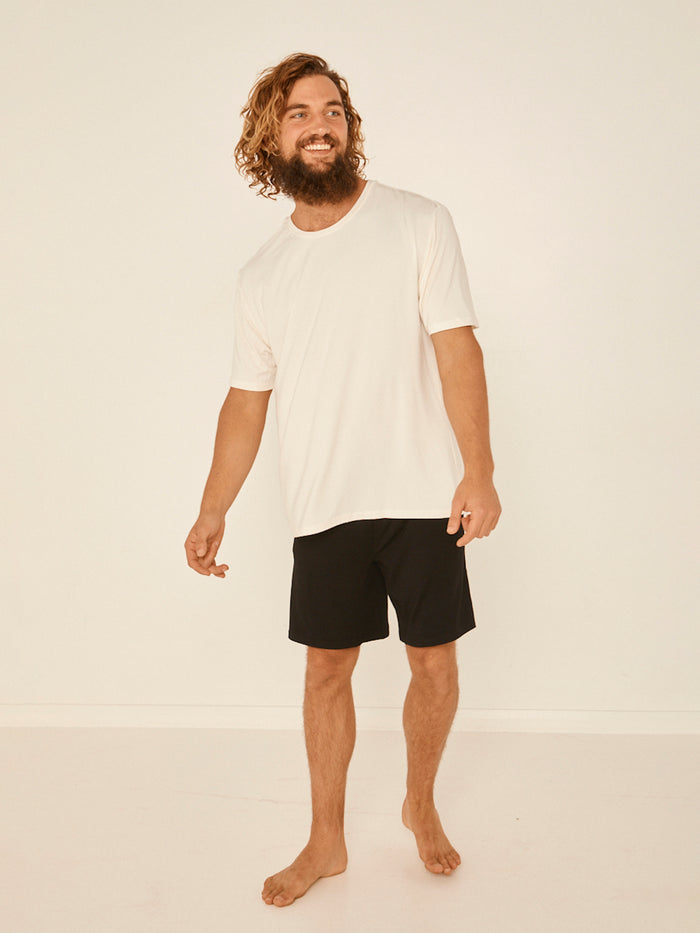 Male model wearing cream generous classic fit tee, soft neckband, crew neckline, short sleeve, men's bamboo clothing