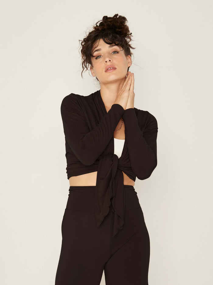 Model wearing convertible black mid cardigan, worn tied at front or worn open with long fitted sleeves, women's bamboo clothing