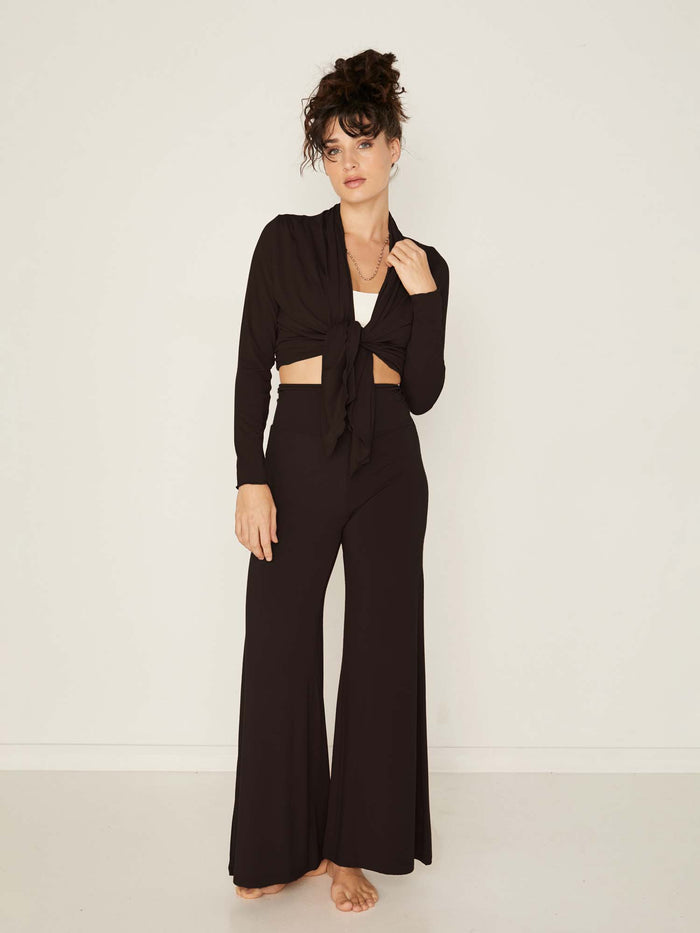 Model wearing convertible black mid cardigan, worn tied at front or worn open with long fitted sleeves, women's bamboo clothing