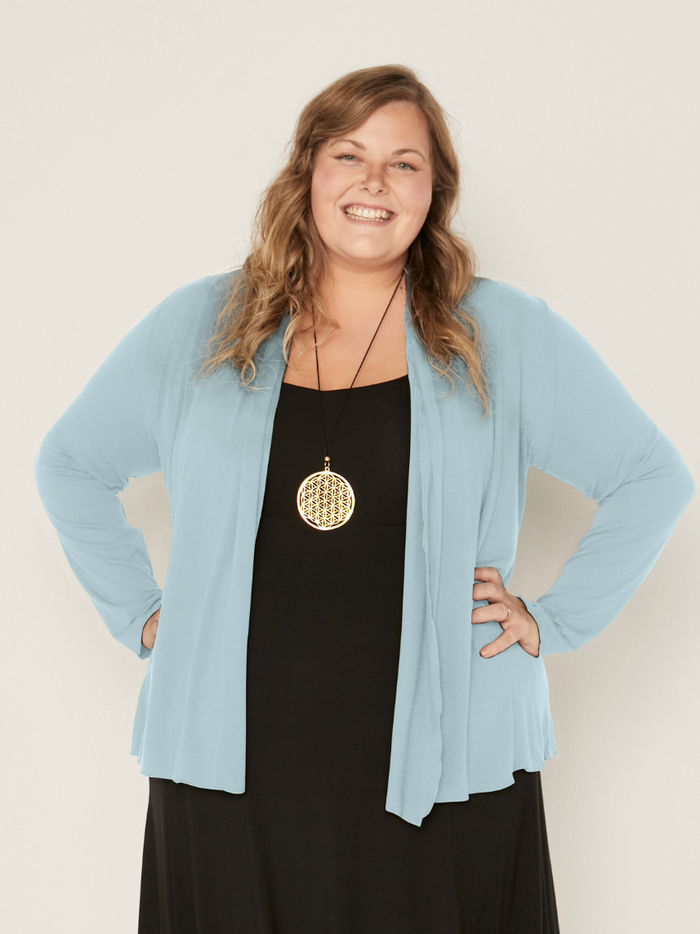 Woman wearing a bamboo topaz blue mid cardigan over a black dress against a white background