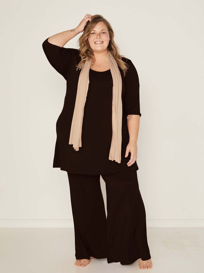 Model wearing black full length palazzo pants, fitted waist and hips with flowing wide leg, adjustible high waistband, women's bamboo clothing