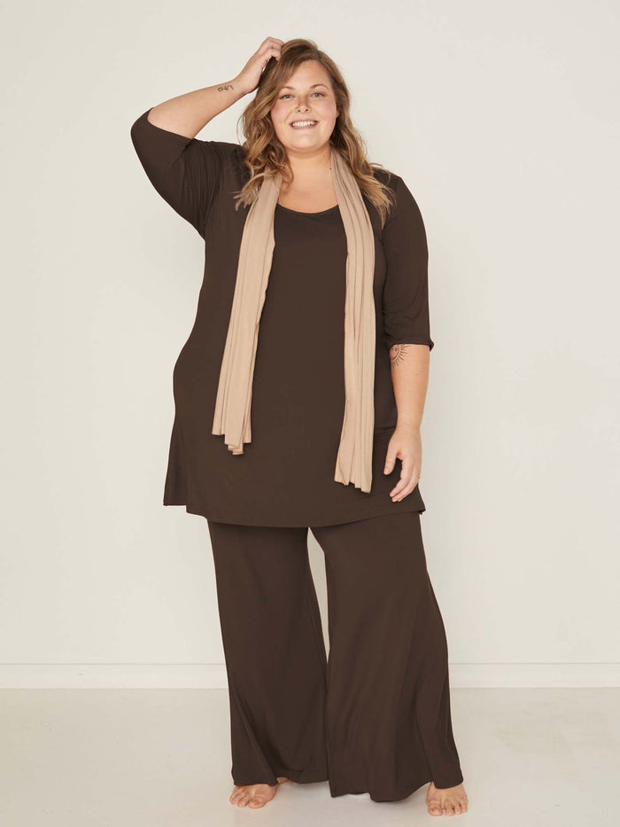 Model wearing cocoa full length palazzo pants, fitted waist and hips with flowing wide leg, adjustable high waistband, women's bamboo clothing