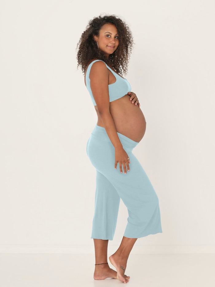 pregnant woman wearing a bamboo light topaz blue reversible bra and 3/4 length resort pants on a white background