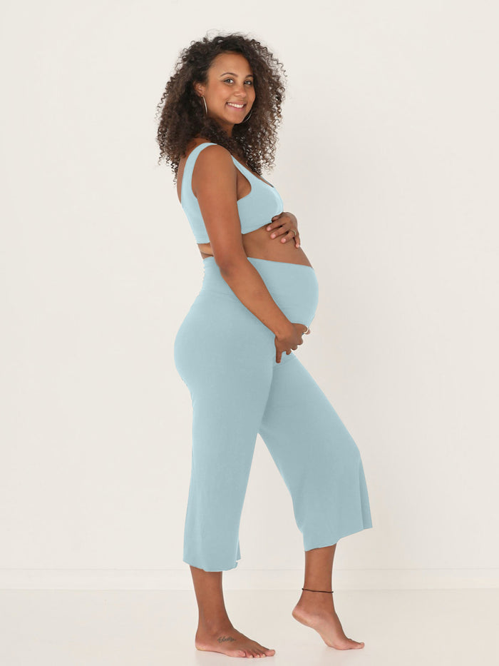 pregnant woman wearing a bamboo light topaz blue reversible bra and 3/4 length resort pants on a white background