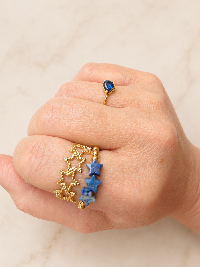 Close-up of a hand wearing VEITA ring stack: Betsy Stretch Gemstone Ring and Textured Star Ring on index finger and Rosie Ring on ring finger.