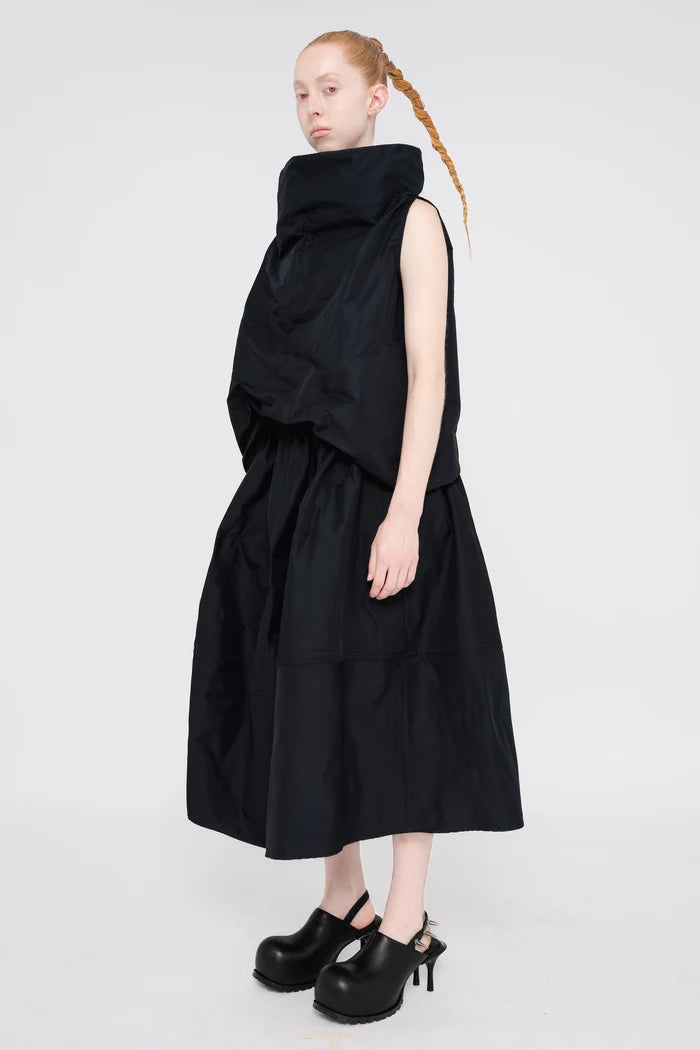 blonde-female-model-white-background-black-sleeveless-boatneck-top-and-skirt-red-eyes-and-black-spikey-doubled-heeled-mules-full-body-quarter-turn