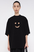 PERSON-WEARING-BLACK-TEE-WITH-SMILEY-FACE-CUT-OUT-AND-BLACK-PANTS-HOLDING-BLACK-BAG-CLOSE-UP-FRONT-VIEW
