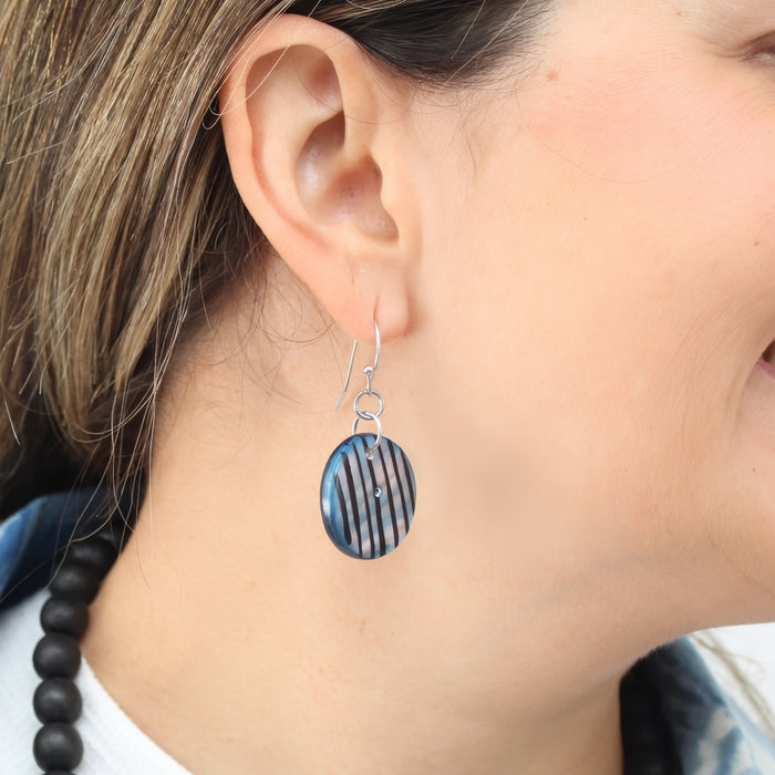 Close-up of a person wearing a black and blue striped earring.