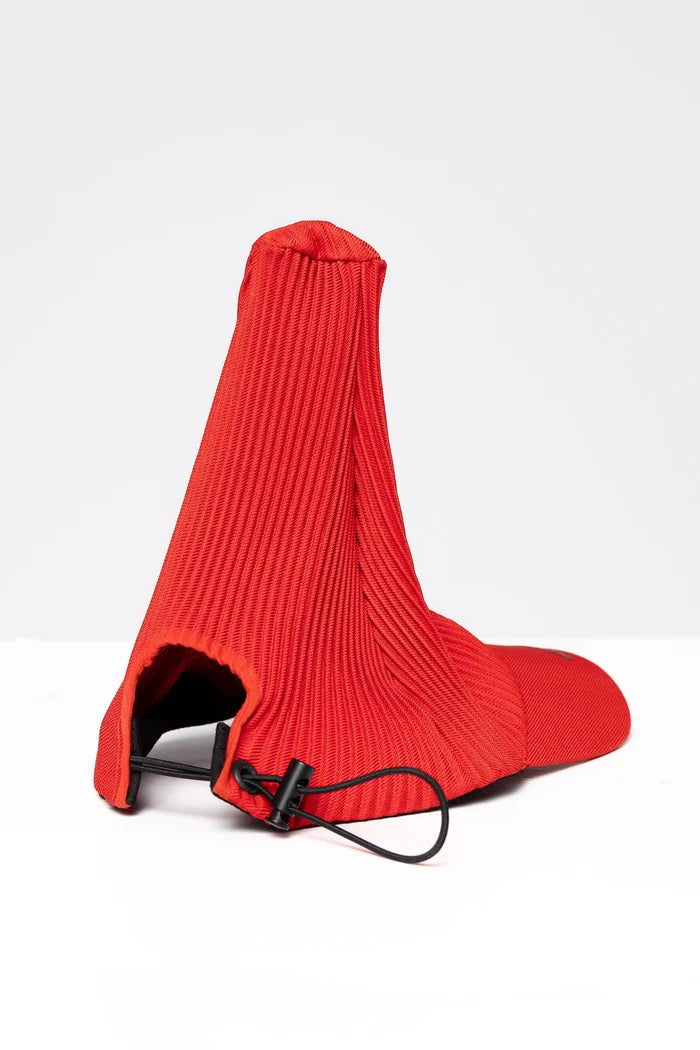 A red baseball cap with the head portion made of a pleated fabric which points upwards.