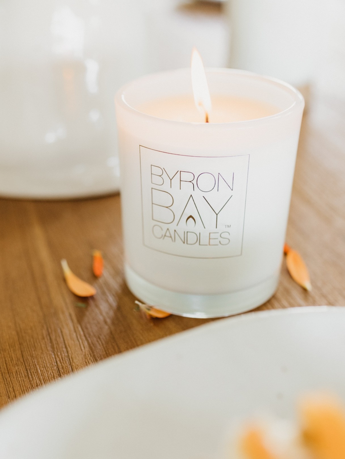 Candle with Byron Bay Candles logo on a wooden surface