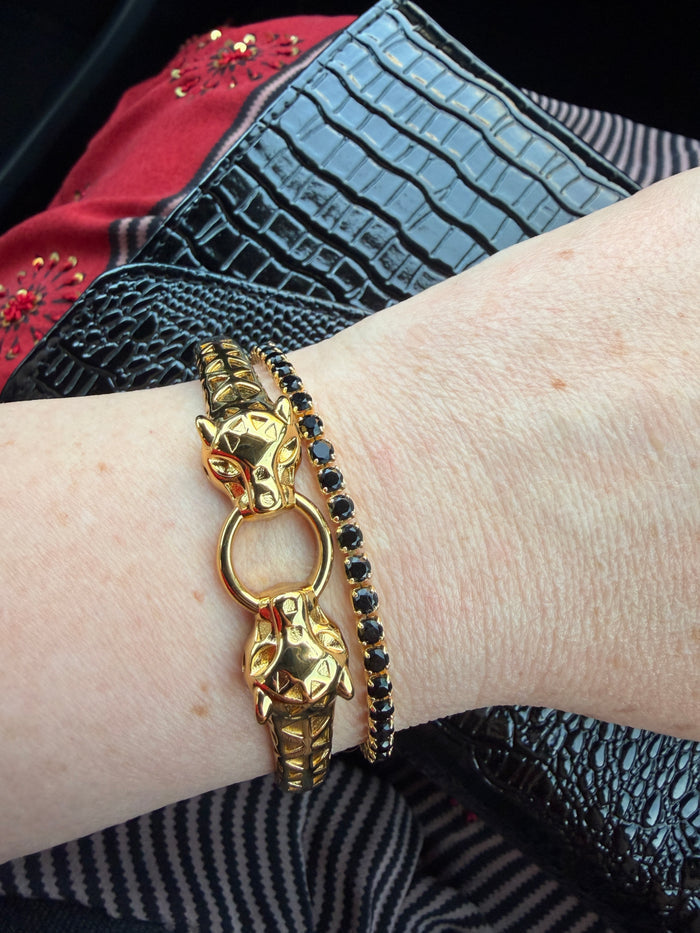 Close-up of gold feline-inspired bangle worn on wrist, highlighting hinge closure and detailed texture