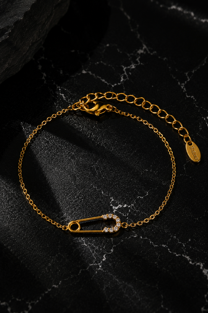 Delicate Salama Bracelet in gold featuring a delicate safety pin design crafted from stainless steel with 18kt gold plating and sparkling zircon accents.