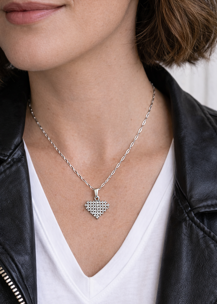 Person wearing a silver necklace with a heart-shaped pendant.