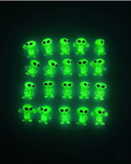 Green alien figurines glowing in the dark on a black background