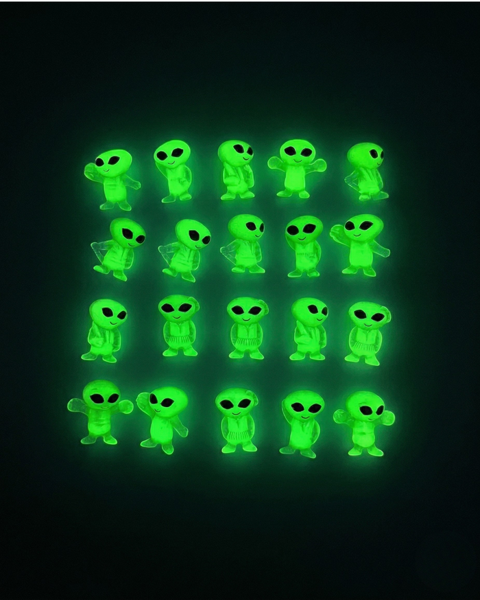 Green alien figurines glowing in the dark on a black background