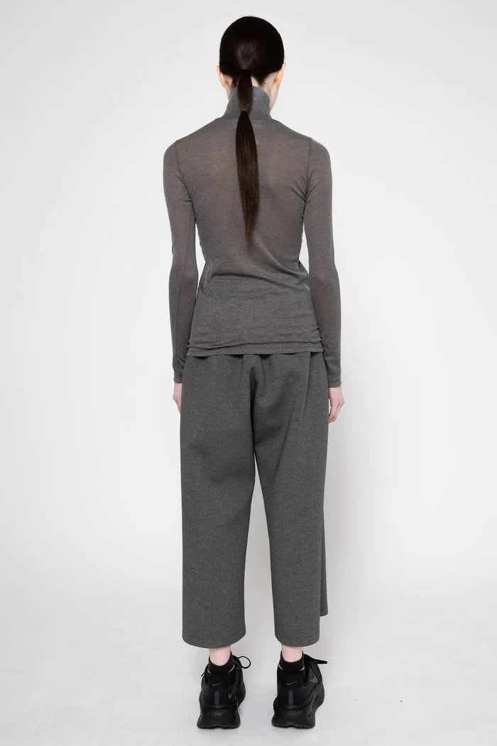 A model shown from the back wearing a dark gray ribbed long-sleeve mock neck top and matching wide-leg cropped pants, paired with black platform sneakers, against a plain white studio background.