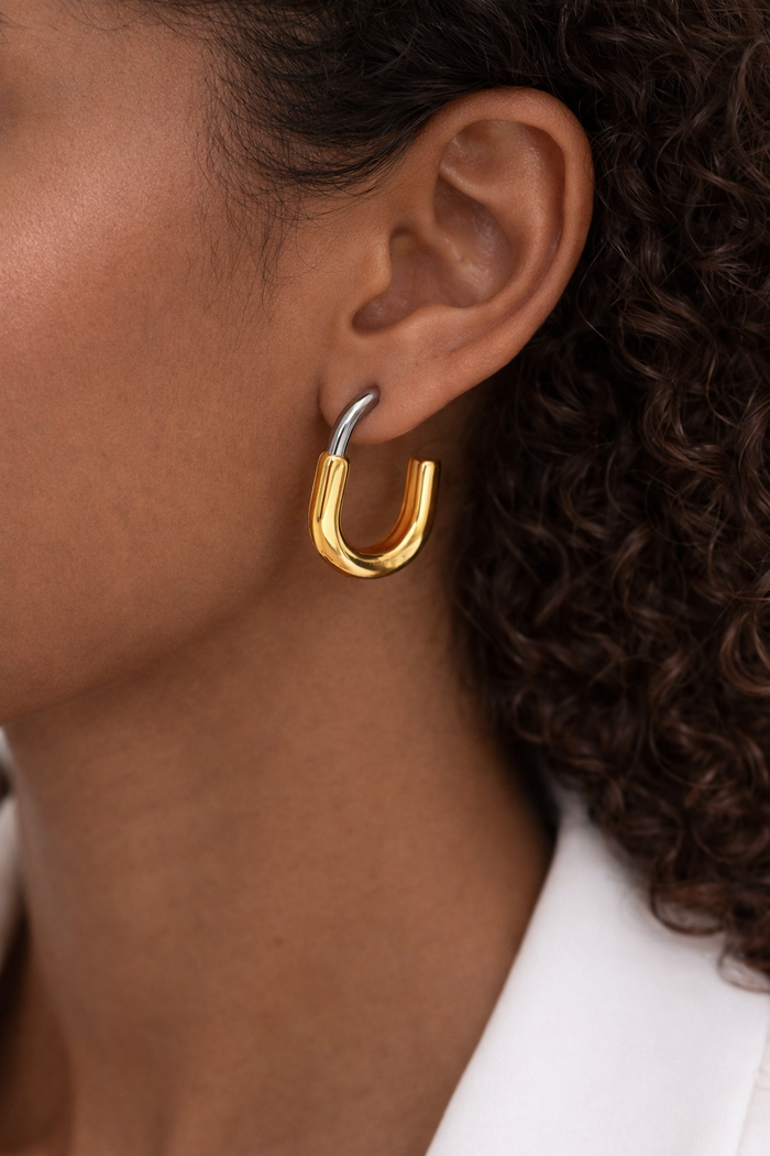 Gold hoop earring worn by a person with curly hair.