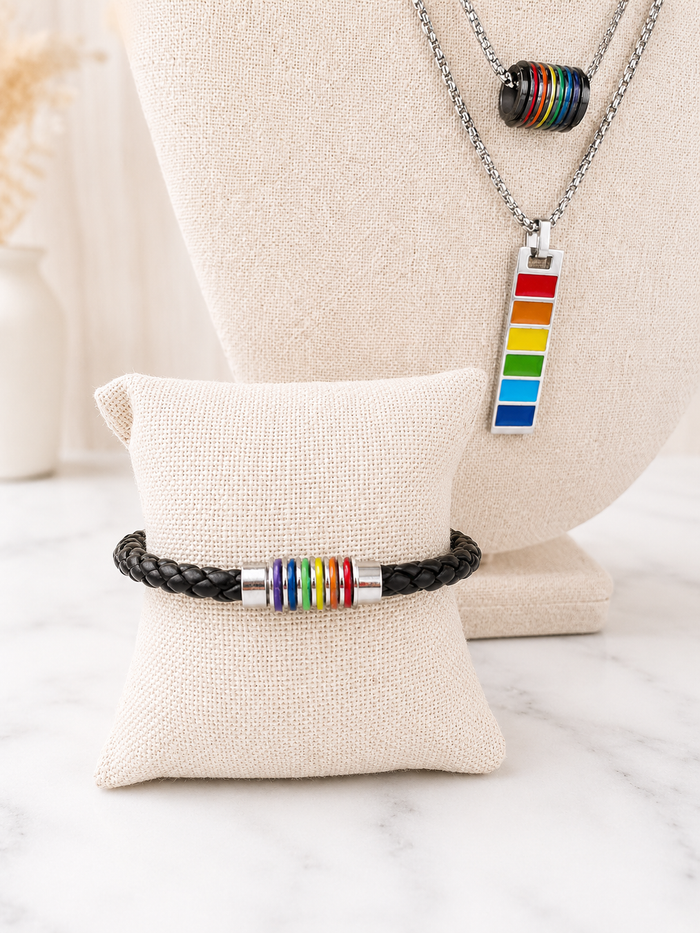 Harvey Barrel Necklace with Pride rainbow pendant styled necklace with a black leather Pride bracelet with rainbow barrel beads on linen jewelry displays