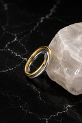 Interwoven Mixed Metal Ring featuring intertwined stainless steel bands with 18kt gold plating displayed on a crystal accent.