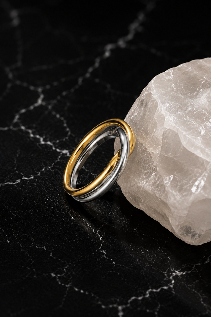 Interwoven Mixed Metal Ring featuring intertwined stainless steel bands with 18kt gold plating displayed on a crystal accent.