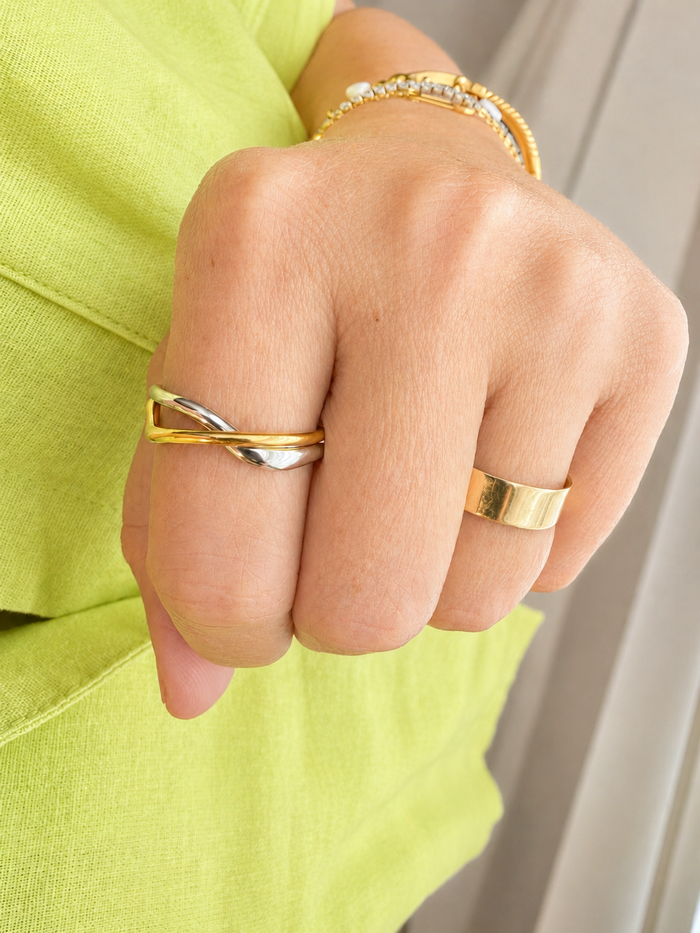 Model wearing the Interwoven Mixed Metal Ring featuring intertwined stainless steel bands with 18kt gold plating.