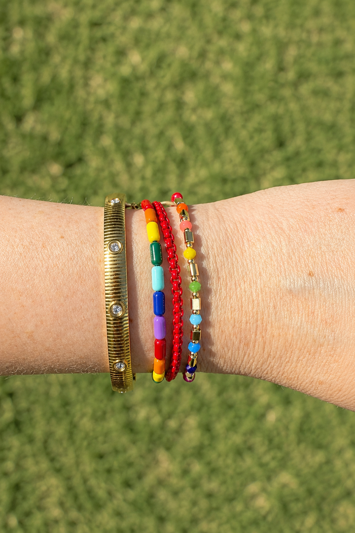 Prism and Iris Adjustable Bracelet stacked with colorful beaded bracelets worn on a wrist outdoors