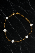 Kate Layering Bracelet featuring delicate mother of pearl accents on an 18kt gold-plated stainless steel chain displayed on a black marble surface.