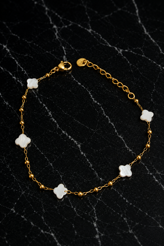 Kate Layering Bracelet featuring delicate mother of pearl accents on an 18kt gold-plated stainless steel chain displayed on a black marble surface.