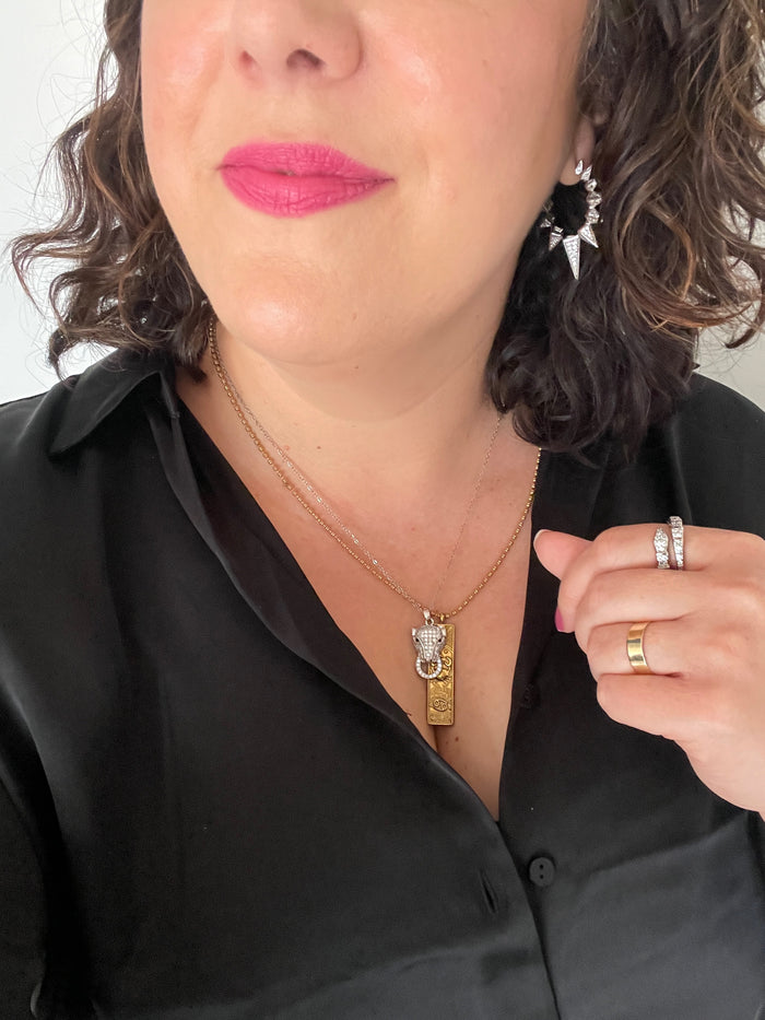 Close-up of a person wearing a necklace with a pendant, black shirt, and jewelry.