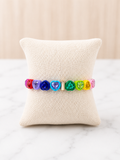 Love is Love Bracelet with rainbow heart-shaped gemstones on a linen jewelry pillow