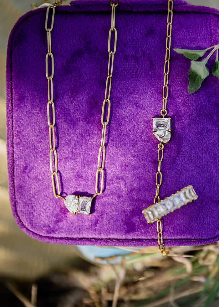 Purple velvet jewelry box case with gold necklaces on a natural background