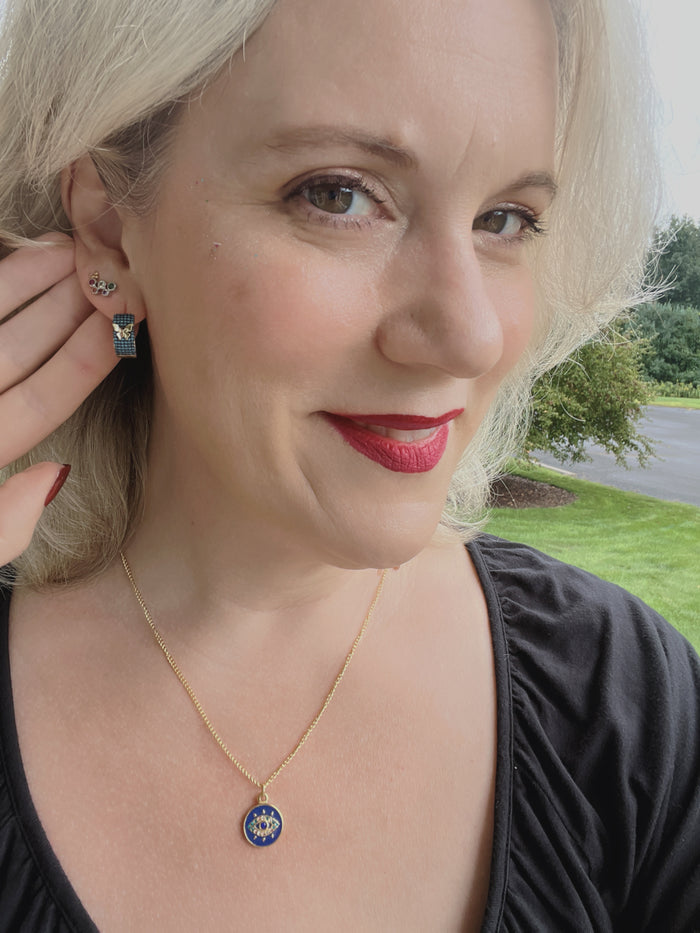 Model wearing the VEITA Jewelry Safira Necklace featuring a blue enamel protective eye pendant on a delicate gold chain