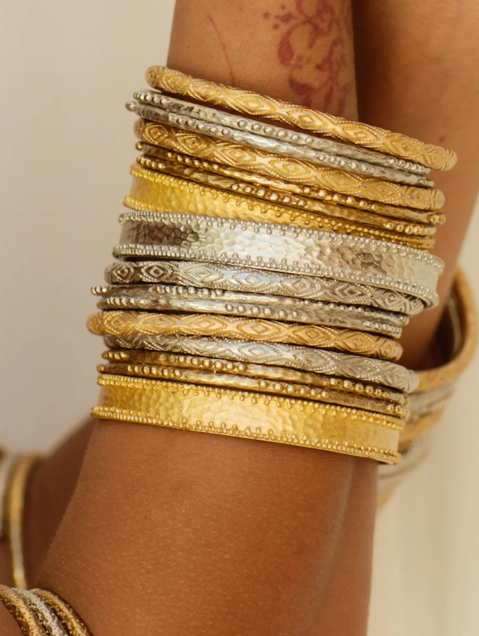 Stack of gold and silver bangles on a wrist with a neutral background