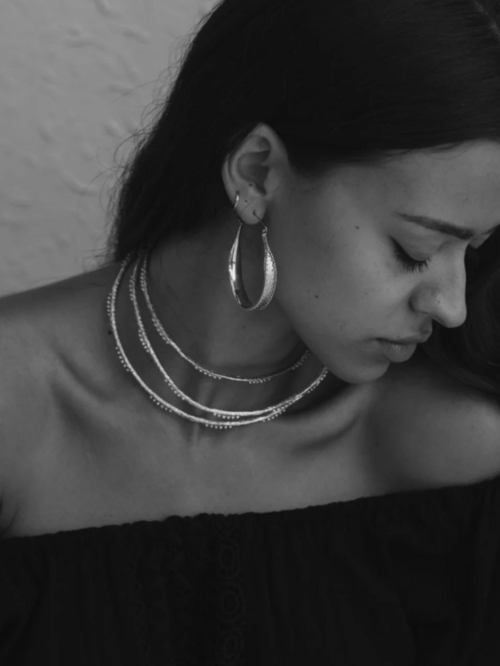 Black and white photo of a lady wearing silver hoop earrings.