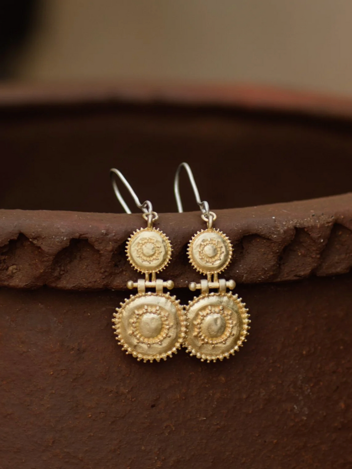 Gold earrings on a textured brown surface