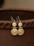 Gold earrings on a textured brown surface