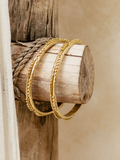 Gold bracelets on a wooden block with a natural background
