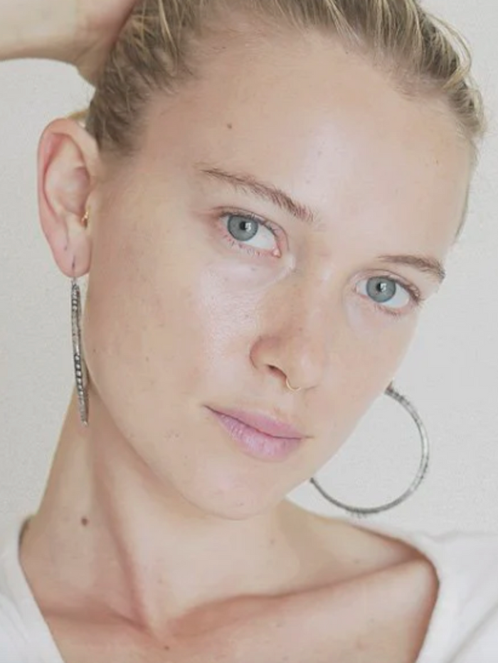 Close-up of a person wearing hoop earrings on a plain background