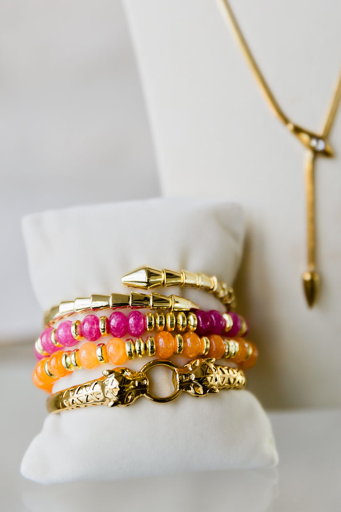 Night Coil gold bangle styled with colorful bracelets in a stacked wrist look highlighting versatile layering options