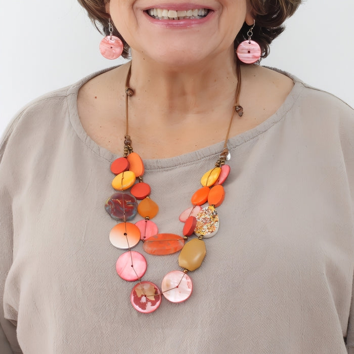 Woman wearing a colorful necklace with a plain background