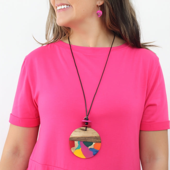 Woman wearing a colorful large necklace with a pink top on a white background