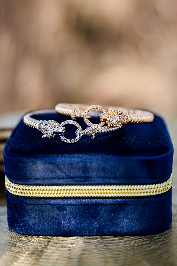 Panther head bangle bracelet with pavé stones displayed on blue velvet jewelry box